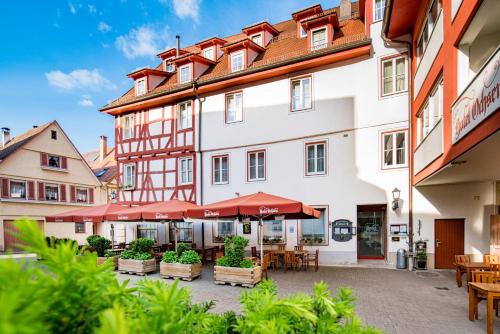 a hotel with tables and umbrellas in a courtyard at Hotel-Restaurant Ochsen in Blaubeuren