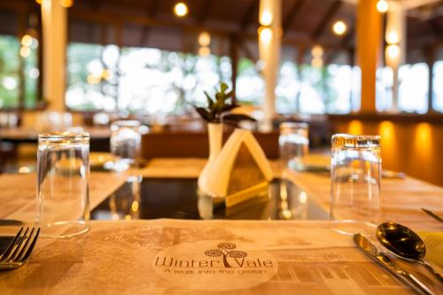 
a table with a glass of wine on it at Winter Vale Green Stay Resorts in Vagamon
