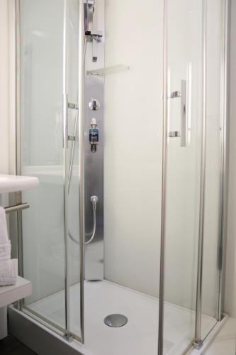 a shower with a glass door in a bathroom at Le Quarré Hôtel Bistrot in Bruguières