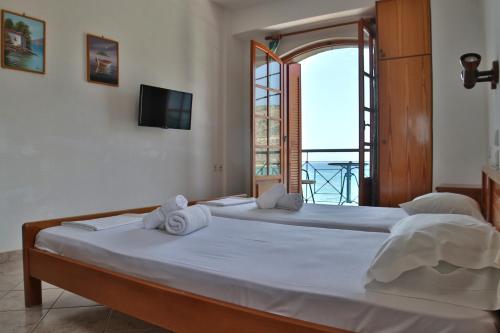 a bedroom with two beds and a tv and a window at Guesthouse Palataki in Neo Itilo