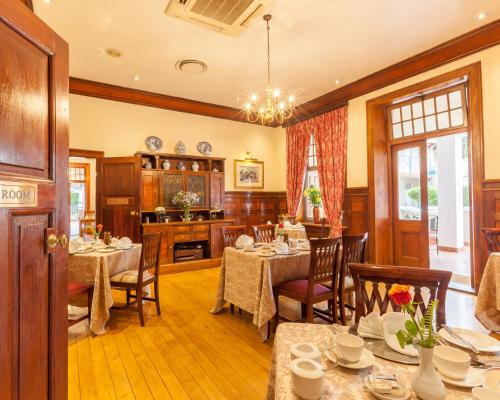 a dining room with tables and chairs and a kitchen at Courtyard Hotel Arcadia in Pretoria