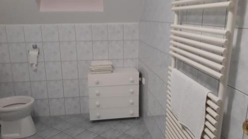 a white bathroom with a toilet and a sink at Szalóky Apartmanház in Gyenesdiás