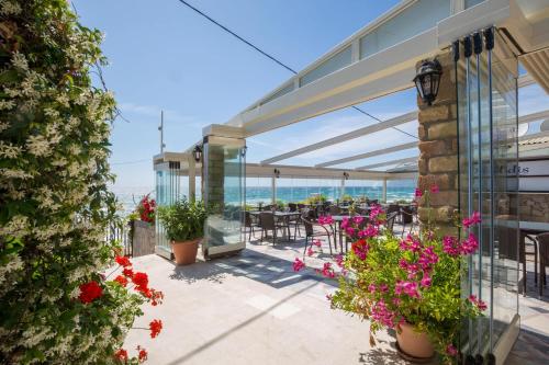 a patio with a view of the ocean and flowers at Dandidis Seaside Pension in Agios Gordios