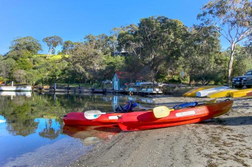 a red kayak sitting on the shore of a body of water at Jetty Road Retreat in Nungurner