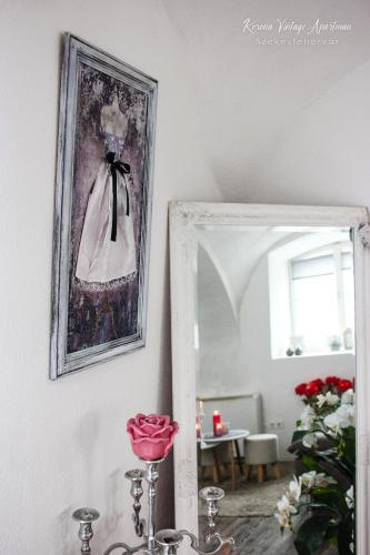a mirror in a room with a picture of a dress at Korona Apartman Székesfehérvár in Székesfehérvár