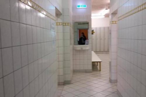 a hallway with white tiled walls and a person in a mirror at moderne Ferienwohnung mit WLAN+Schwimmbad+Sauna in Hohegeiß