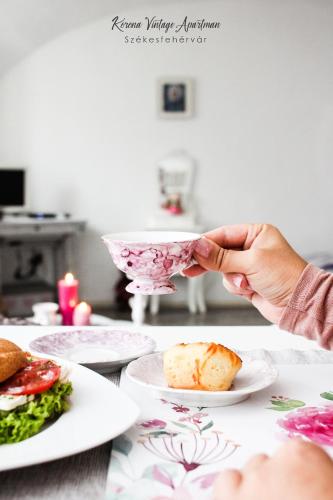 a person holding a bowl over a table with plates of food at Korona Apartman Székesfehérvár in Székesfehérvár