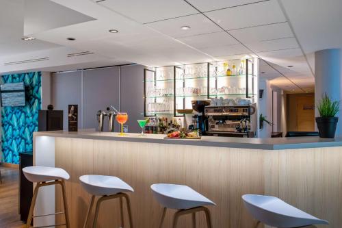 a bar in a restaurant with white stools at Best Western Plus Hôtel Vannes Centre Ville in Vannes