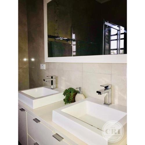 a bathroom with two white sinks and a mirror at The Cri on Main in Grenfell