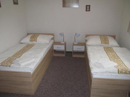 two beds in a room with two lamps on tables at A+S Penzion Podzamok in Spišské Podhradie