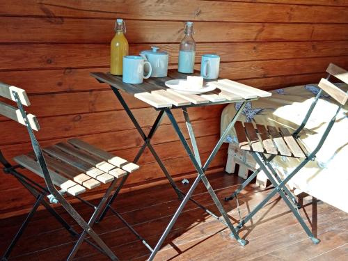 stół z 2 krzesłami i 2 butelki wina w obiekcie Wee Hoose Glamping 3 w mieście Kinbrace