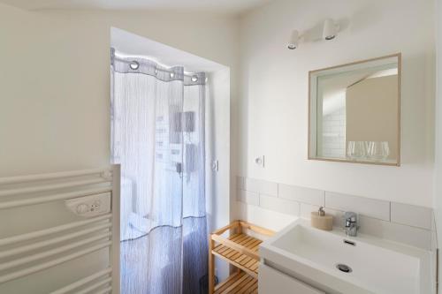 ein weißes Badezimmer mit einem Waschbecken und einem Spiegel in der Unterkunft LA DEROBEE - Havre de paix en ville in Rennes