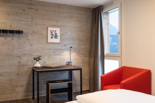a bedroom with a desk and a red chair at B&B Hotel Mattli Übernachtung Frühstück in Morschach