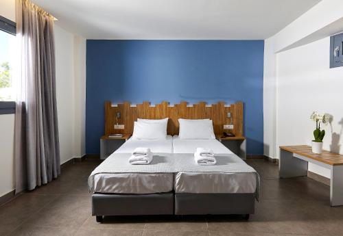 a blue bedroom with a bed with towels on it at Pollis Hotel in Hersonissos