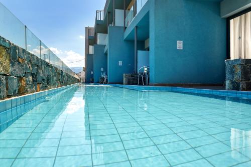 a swimming pool in a building with blue walls at Pollis Hotel in Hersonissos