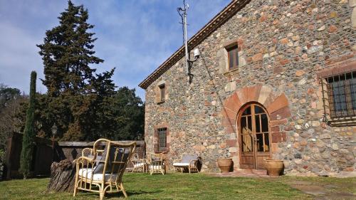 a group of chairs sitting outside of a stone building at Masia Can Bachs in Sant Pere de Vilamajor