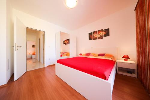 a white bedroom with a red bed in a room at Villa Pino with Pool, Sauna & Jacuzzi in Petrcane