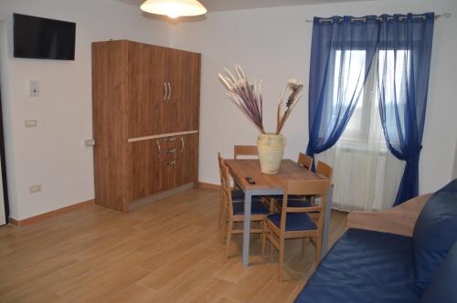 a living room with a table and a cabinet and blue curtains at I fiori del Pollino - Guest House in San Severino Lucano