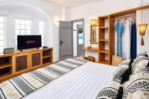 a bedroom with a bed and a tv in it at San Marino Suites by Calm Collection in Fira