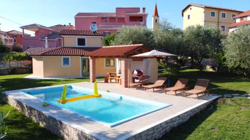 una piscina in un cortile con sedie e una casa di DAMJANIĆ HOLIDAY HOUSE a Brtonigla (Verteneglio)