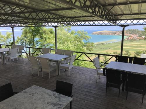 a patio with tables and chairs and a view of the water at Hotel Camping Lin in Pogradec