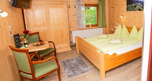 ein Schlafzimmer mit einem Bett, einem Tisch und einem Stuhl in der Unterkunft Frühstückspension Knappaschneider in Prägraten