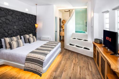 a bedroom with a bed and a flat screen tv at San Marino Suites by Calm Collection in Fira