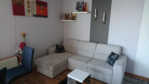 a living room with a white couch and a blue chair at Galerius Golden Beach Apartment in Siófok