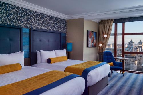 a hotel room with two beds and a balcony at Leonardo Royal Hotel London City - Tower of London in London
