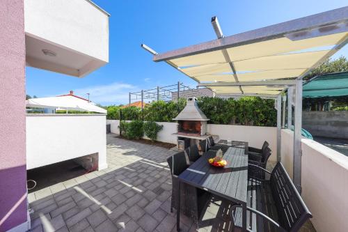 a patio with a grill and a table and chairs at Villa Pino with Pool, Sauna & Jacuzzi in Petrcane