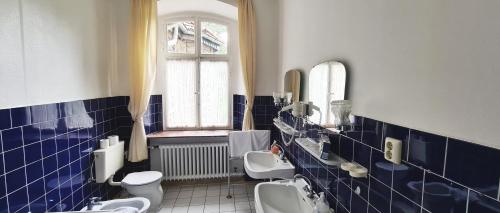 a blue tiled bathroom with two sinks and two toilets at Hotel zum Schwan in Bad Karlshafen