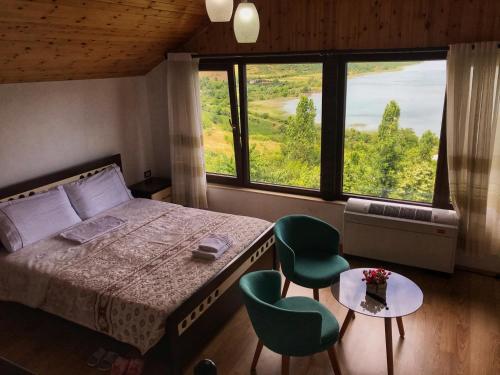 a bedroom with a bed and two green chairs at Hotel Camping Lin in Pogradec