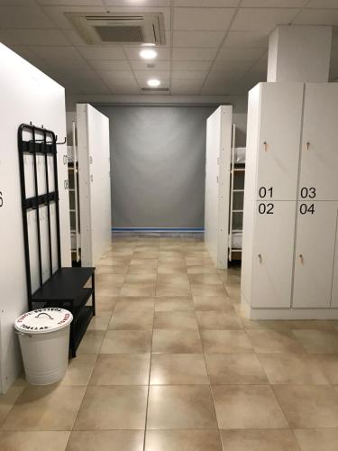 a room with white lockers and a hallway with a floor at Albergue O Pedrón in Padrón