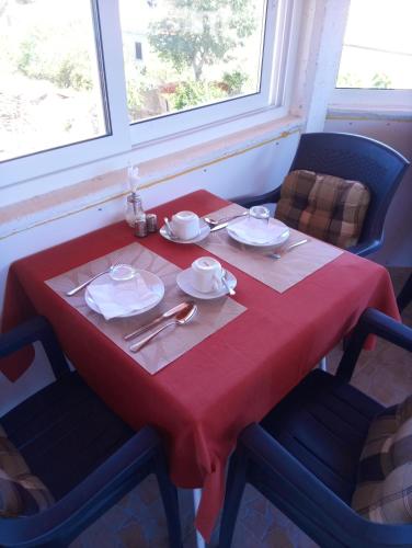 a table with a red table cloth and plates and silverware at Apartments Ruža Dragove Dugi otok in Dragove