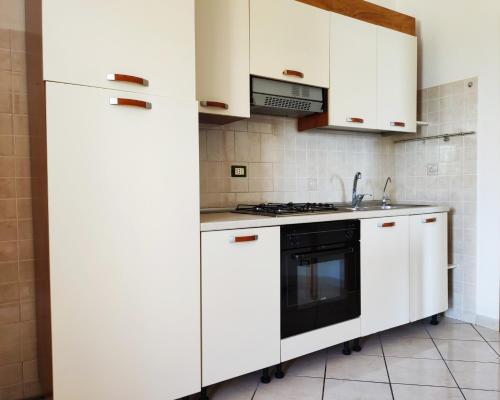 a kitchen with white cabinets and a black oven at Casa De Somma in Ischia