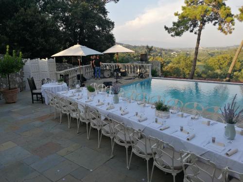 a long table with white tables and chairs next to a pool at Hotel Villa Casanova in Lucca