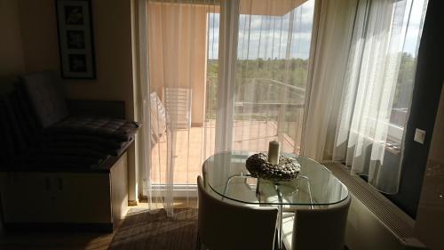 a glass table with a candle on it in front of a window at Galerius Golden Beach Apartment in Siófok
