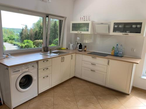 a kitchen with a sink and a washing machine at Leśny domek in Chmielno