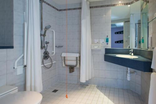 uma casa de banho com um chuveiro, um WC e um lavatório. em Holiday Inn Express London - Wandsworth, an IHG Hotel em Londres