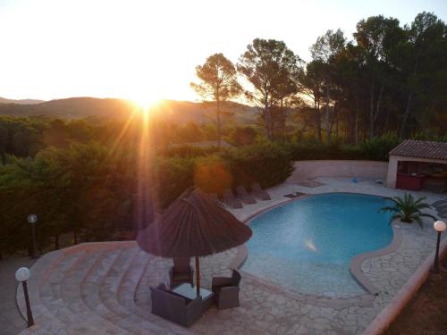a swimming pool with a sunset in the background at La Bastide Des Selves in Draguignan