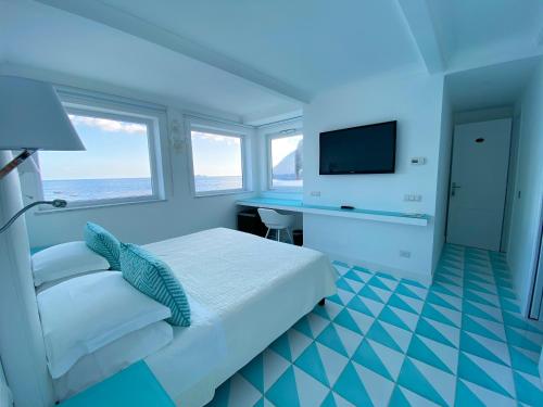 a bedroom with a bed and a desk and a television at La Caravella di Positano - Relais, Beach & Residences in Positano