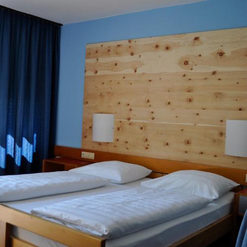 two beds in a bedroom with a wooden headboard at Hotel Leitgebhof in Innsbruck