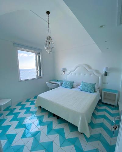 a bedroom with a bed with a blue and white floor at La Caravella di Positano - Relais, Beach & Residences in Positano