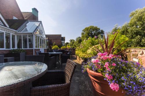 a patio with a table and chairs and flowers at The Moat House in Stafford