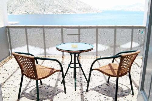Kalymnos Village في ماسوري: طاولة وكرسيين على شرفة مع الشاطئ