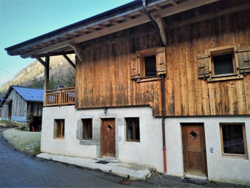 ein Holzgebäude mit Türen und einem Balkon in der Unterkunft Appartement dans ferme rénovée au cœur du Grand Massif in Sixt