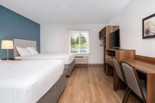 um quarto de hotel com duas camas e uma secretária em WoodSpring Suites Carol Stream - Chicago em Carol Stream