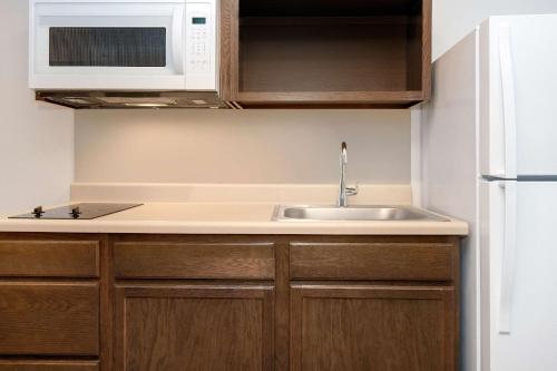 eine Küche mit einer Spüle und einer Mikrowelle in der Unterkunft WoodSpring Suites Carol Stream - Chicago in Carol Stream