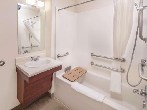 a white bathroom with a sink and a shower at WoodSpring Suites Merrillville in Merrillville