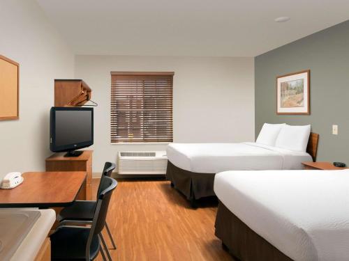 a hotel room with two beds and a desk and a tv at WoodSpring Suites Merrillville in Merrillville